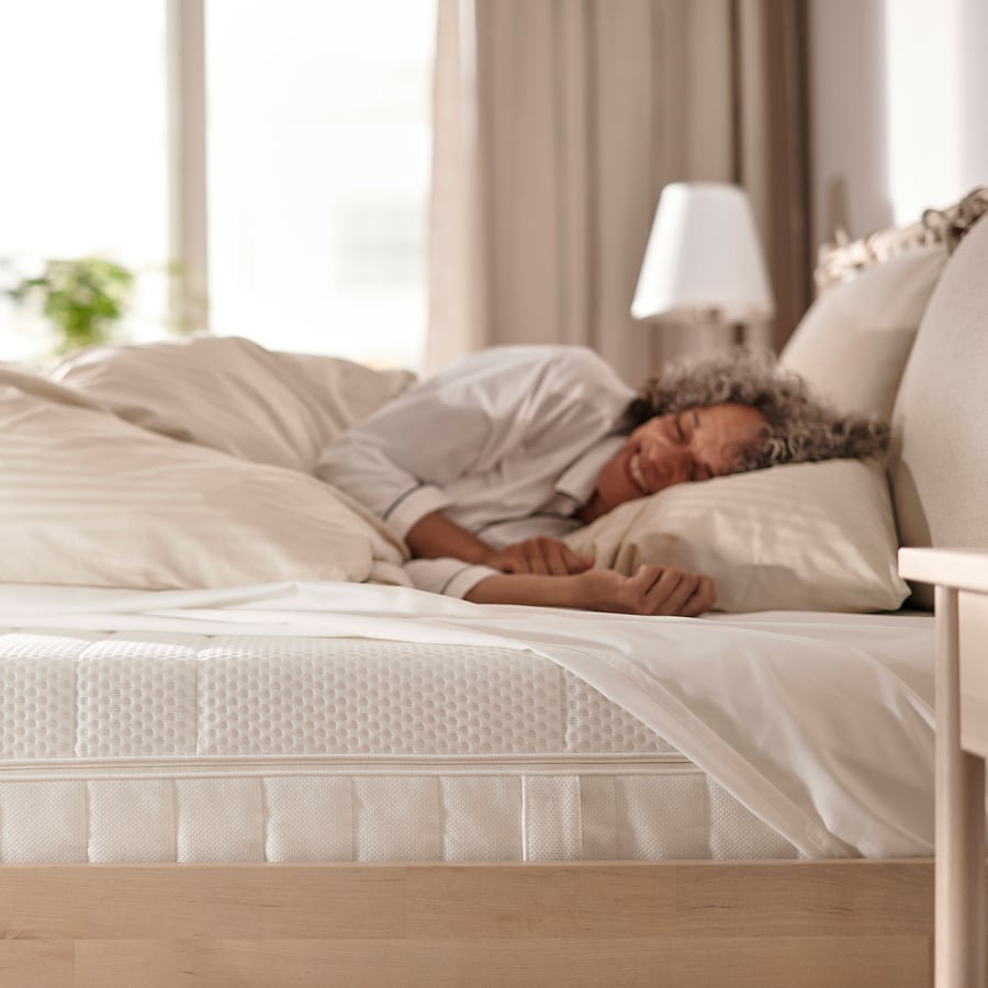 Person asleep on the IKEA Åkrehamn foam mattress in a bedroom