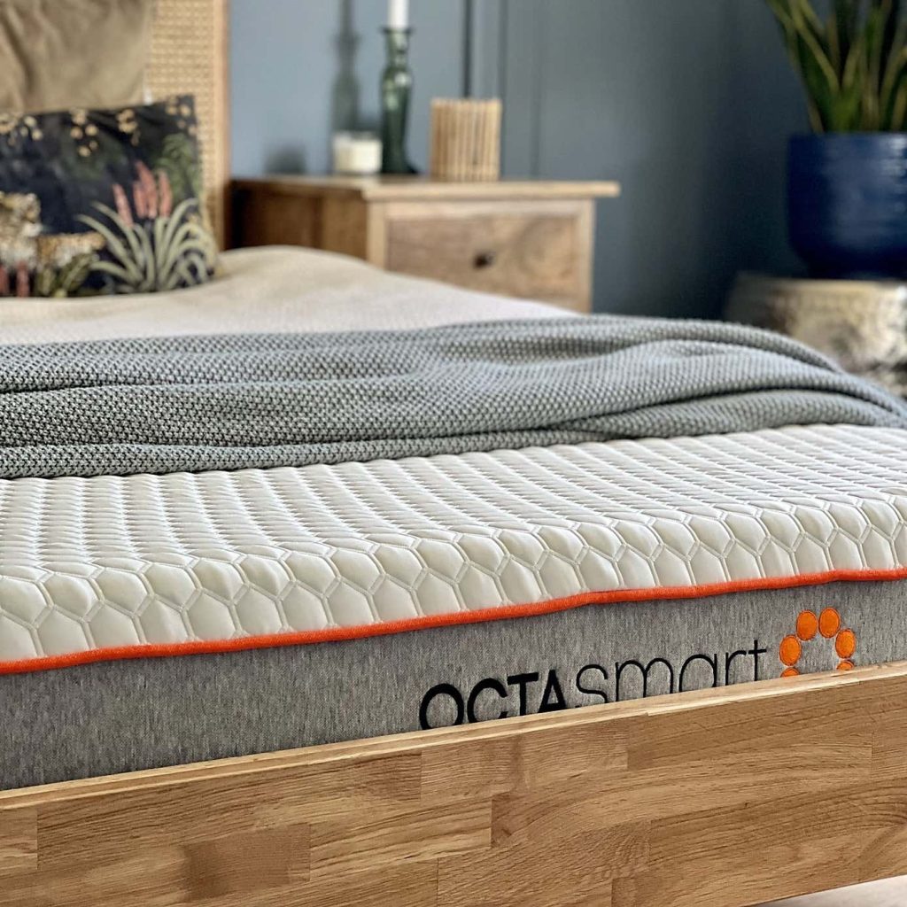 Dormeo Octasmart Plus mattress on a wooden bed frame with a grey throw