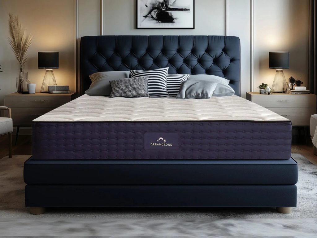 DreamCloud Hybrid mattress on a navy upholstered bed in a softly lit bedroom