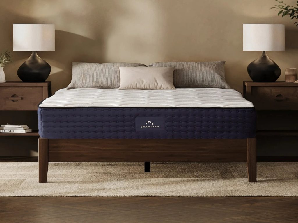 DreamCloud Hybrid mattress on a dark wooden bed frame between two bedside lamps