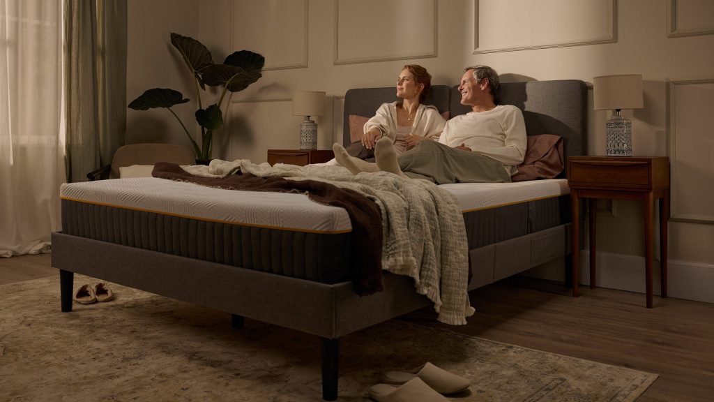 Couple relaxing on an Emma Original Pro mattress in a warmly lit bedroom