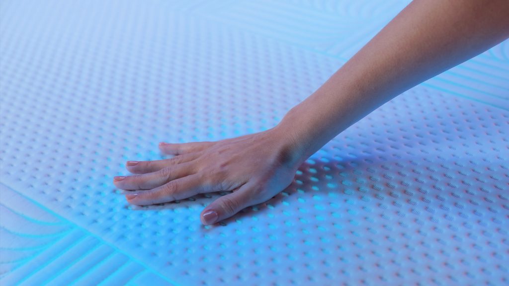 Hand pressing the knitted micro-dot cover of an Emma Performance mattress