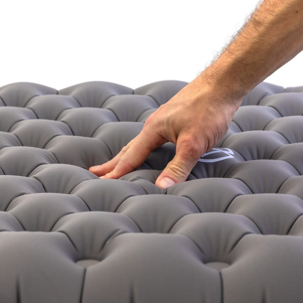 Hand pressing into the stretch knit top of the Zenbivy Flex Air Mattress