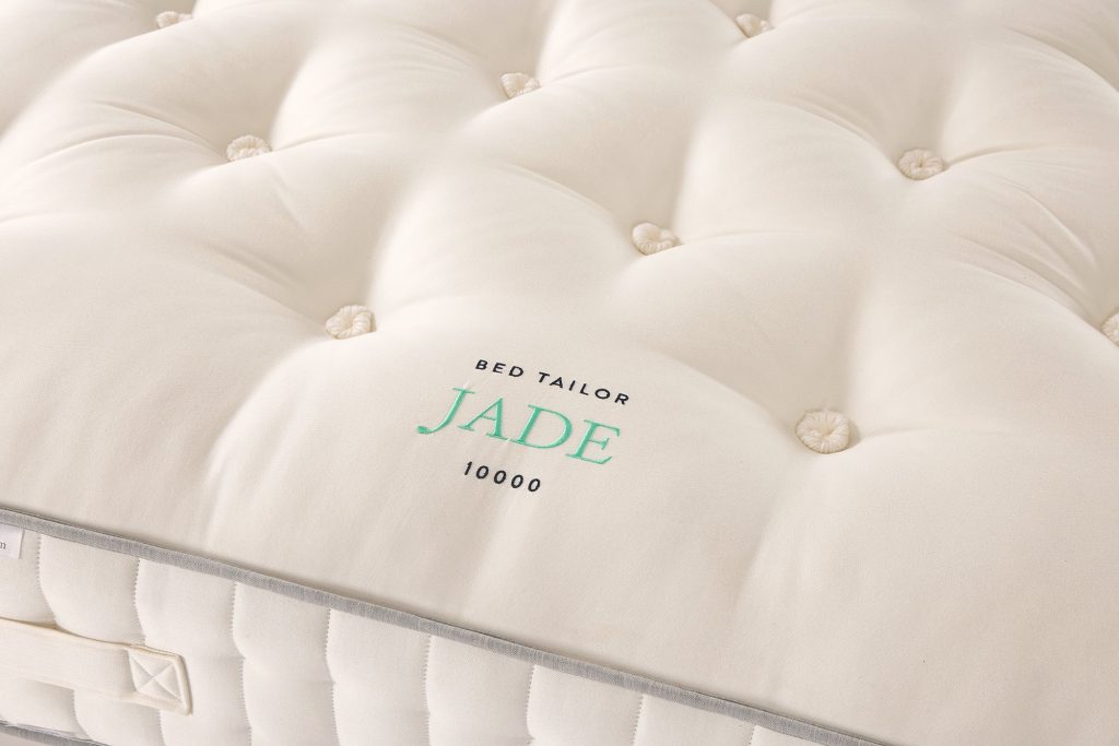 Close-up of the embroidered Jade 10000 label and tufting on the mattress top