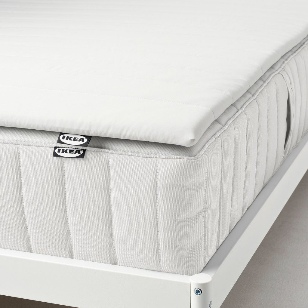 IKEA Nopakte mattress pad on a white sprung mattress, side view of the thin 2.5 cm layer