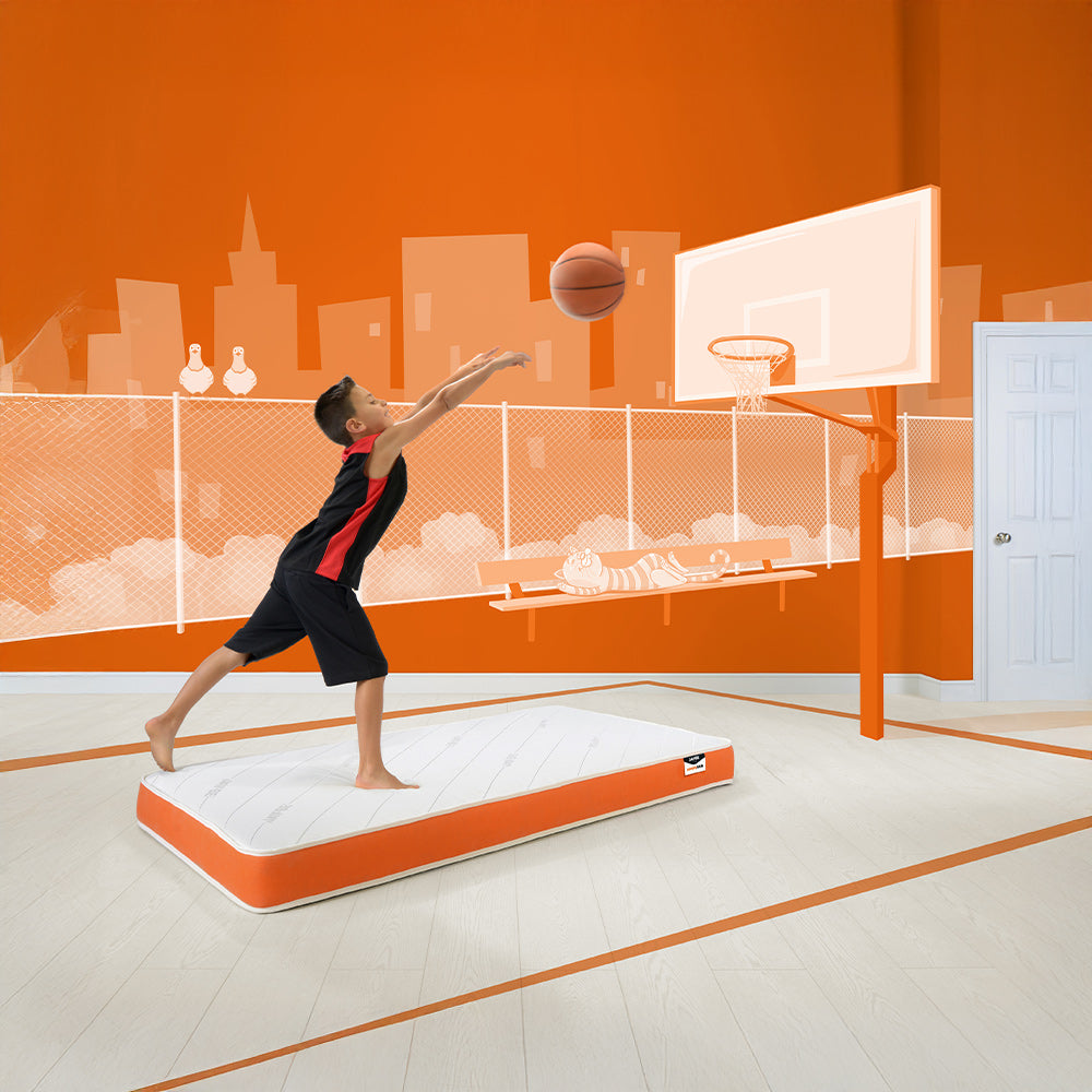 Child playing basketball next to the Jay-Be Simply Kids mattress