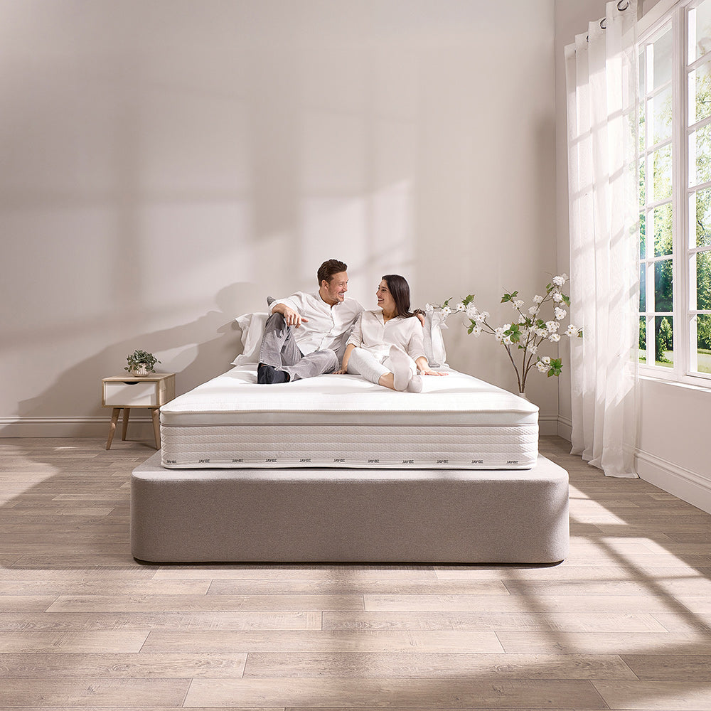 Couple sitting on the Jay-Be Truecore Hybrid 2000 mattress on a divan bed