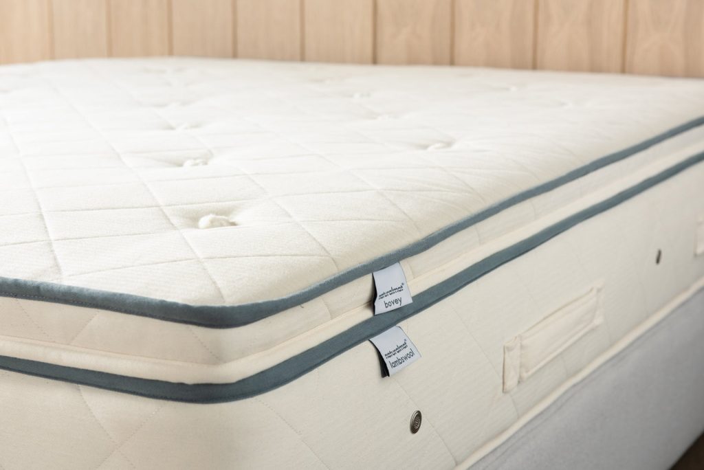 Naturalmat Bovey Topper fitted on a bed with its Naturalmat labels