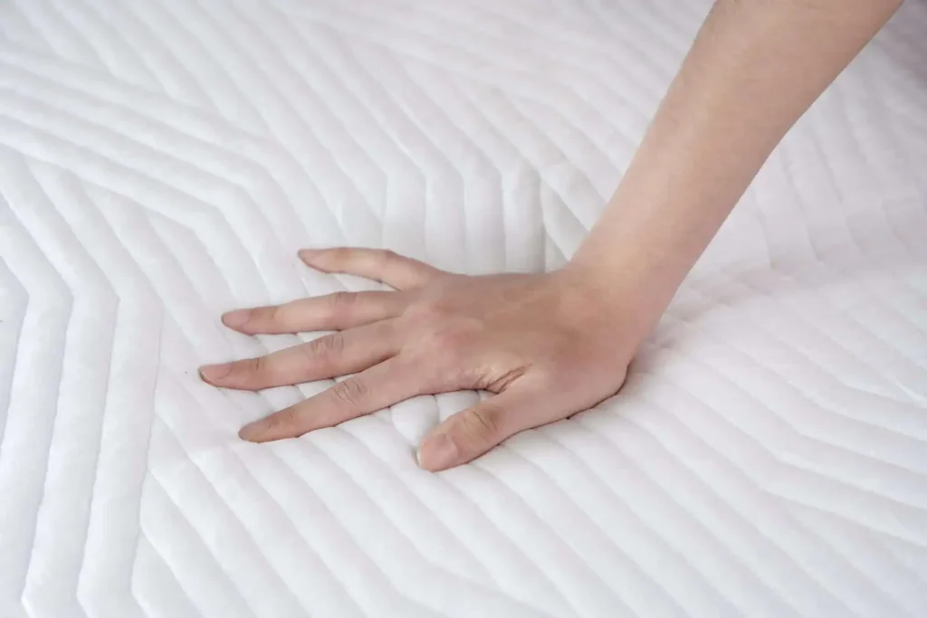 Hand pressing into the quilted cover of the Origin Contour Mattress Topper