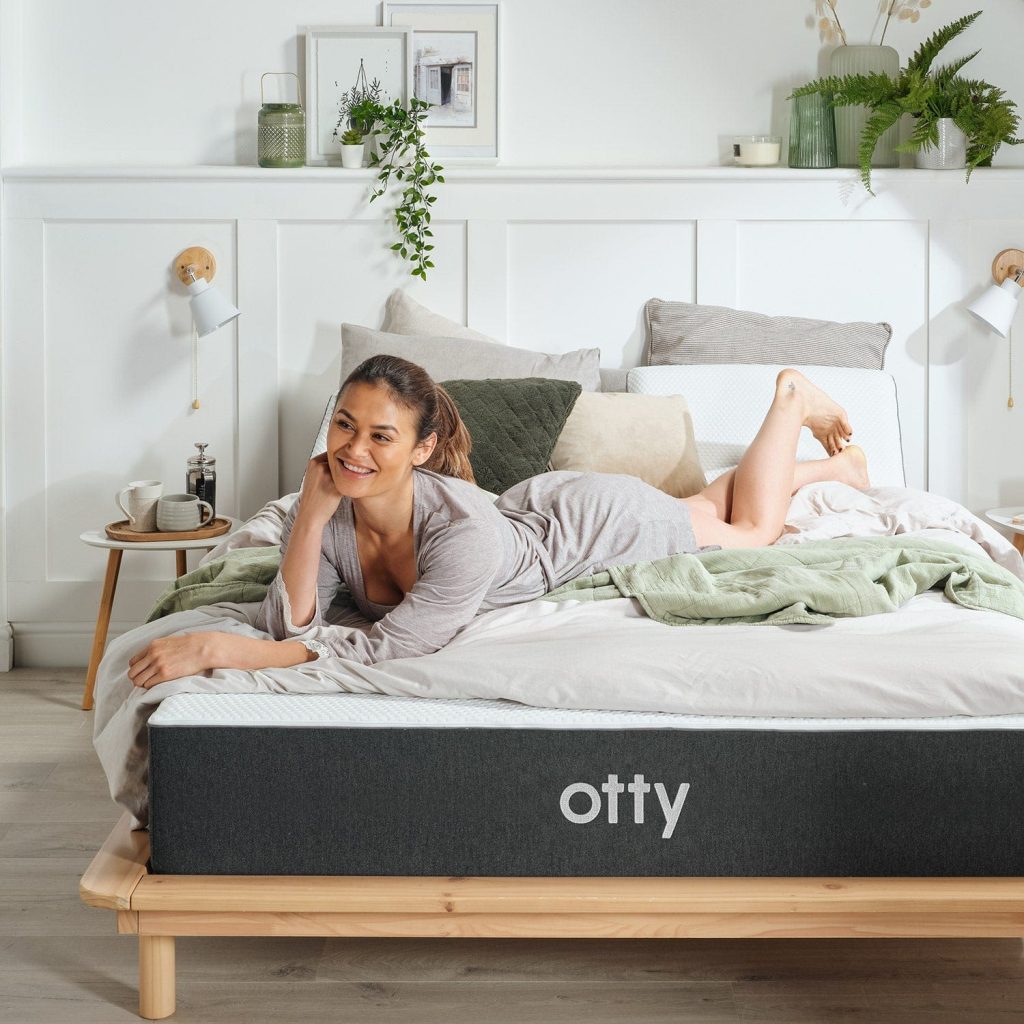 Woman lying on the OTTY Original Hybrid Mattress showing its white knitted top