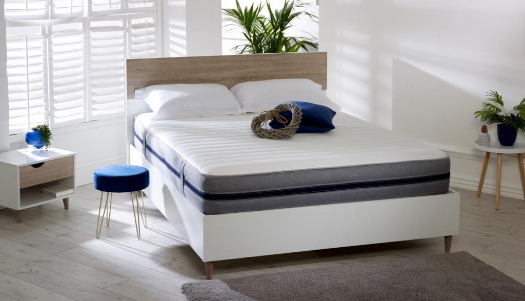 Starlight 07 all-foam mattress on a white bed frame with blue cushion
