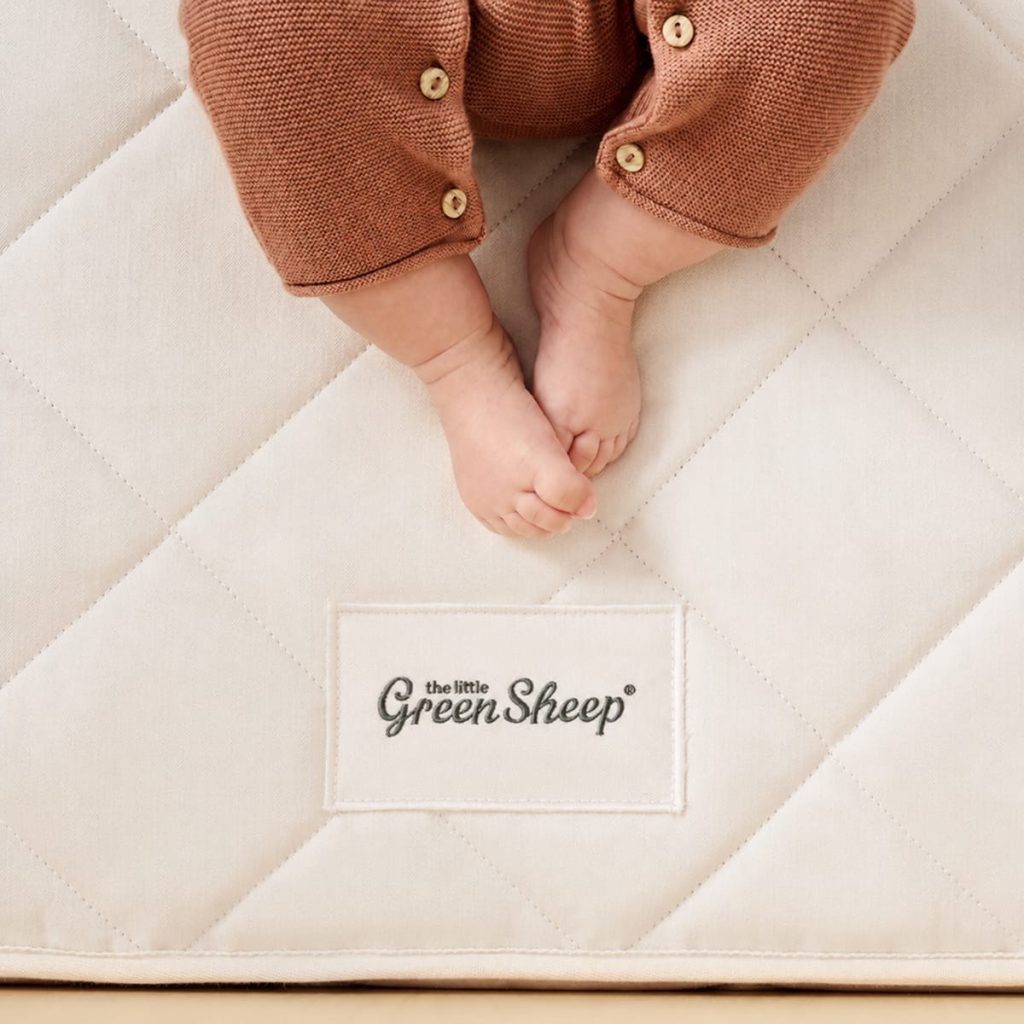 Baby feet on the quilted herringbone cover of The Little Green Sheep Twist Natural Cot Bed Mattress