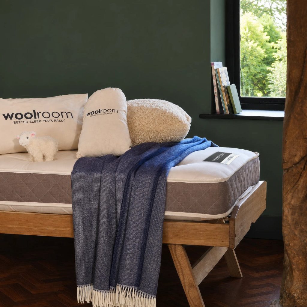 Woolroom Junior mattress on a wooden daybed with wool pillows and a throw