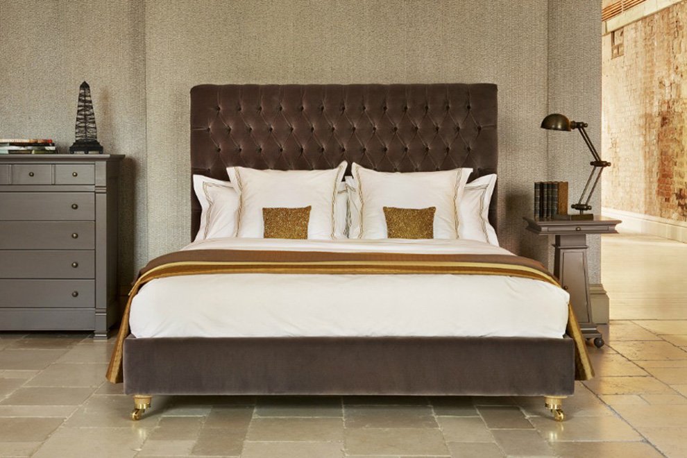 And So To Bed Emilia Grand Bed in mink velvet with brass castors in a stone-floored room