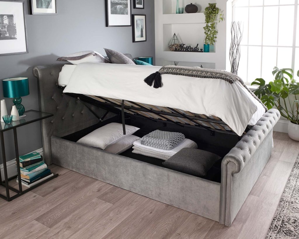 Aspire Scroll Top Chesterfield Ottoman Bed opened to show folded bedding in the storage well
