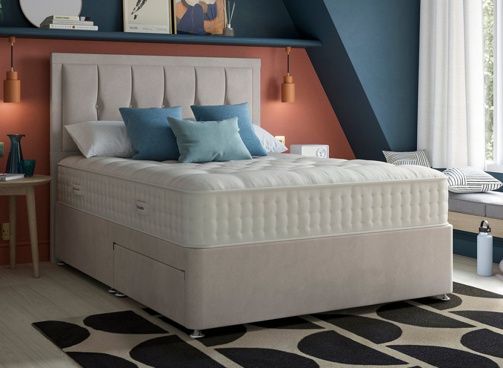 Dream Team Ashbourne mattress on a beige divan bed in a bedroom with a blue wall