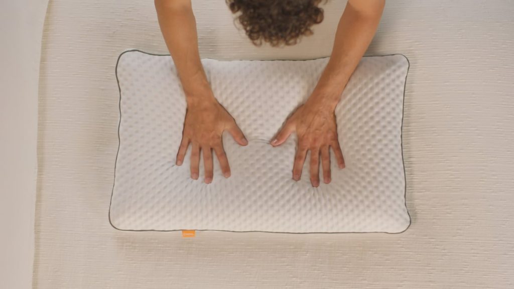 Hands pressing the white knitted cover of the Emma Adapt Cooling Pillow