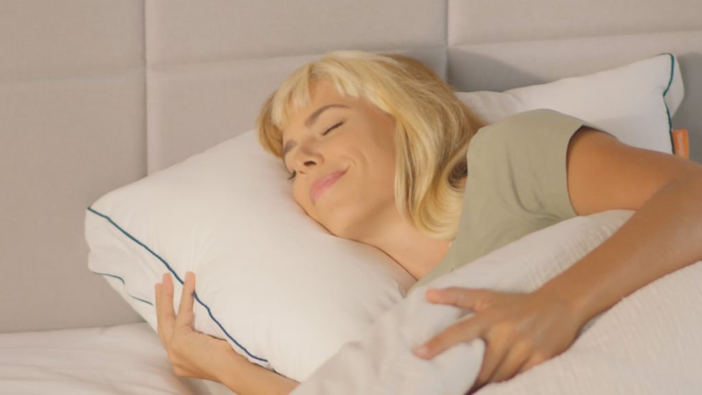 Woman lying on her side hugging an Emma Comfort Cooling Pillow