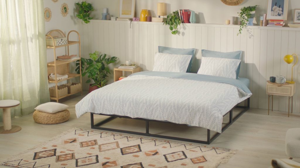 Emma Metal Bed with mattress and blue bedding in a bright bedroom