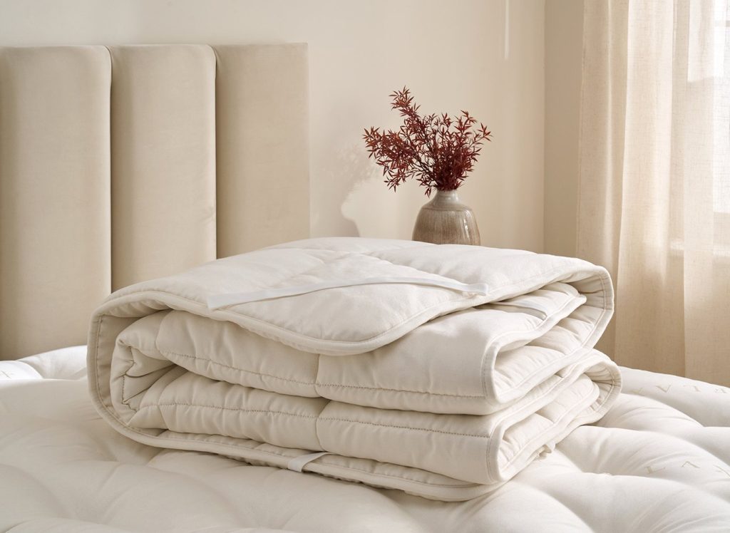 Flaxby Quilted Wool Mattress Enhancer folded on a bed
