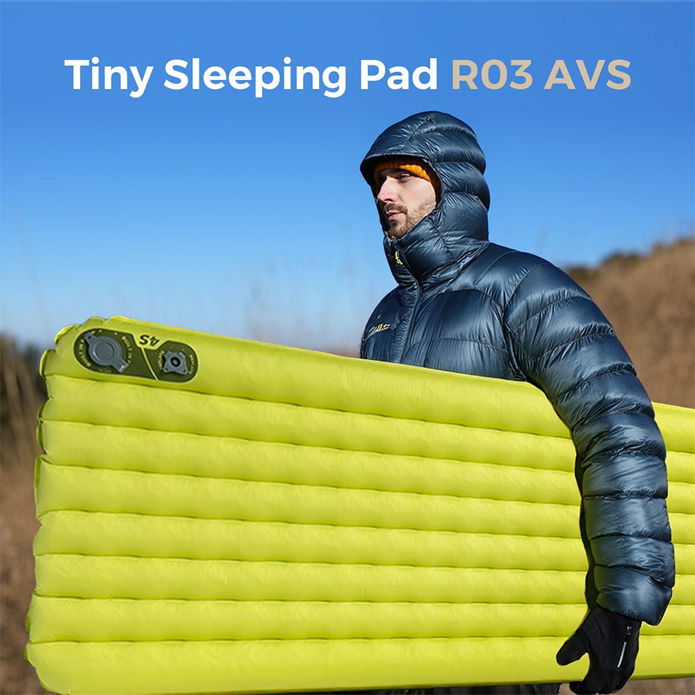 Camper in a down jacket carrying an inflated Flextail Tiny Sleeping Pad R03 AVS outdoors