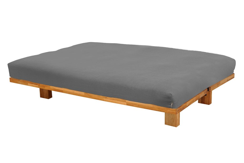 Futon Company Supreme Bifold futon in a grey cover laid flat on a low wooden base