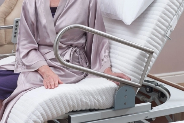 Grab handle lowered beside a user seated on the Laybrook turning bed