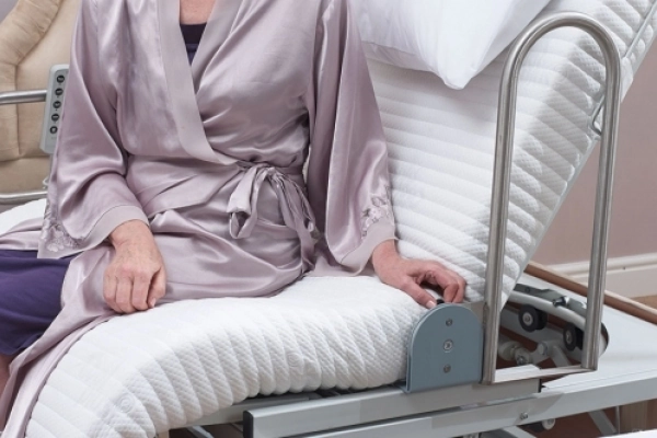 Grab handle raised beside a user seated on the Laybrook turning bed