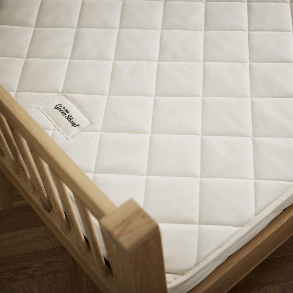Close-up of the quilted cotton cover and label of The Little Green Sheep Natural Junior Mattress