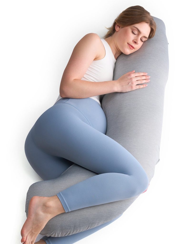 Pregnant woman hugging the grey Momcozy J-shaped pillow while lying on her side