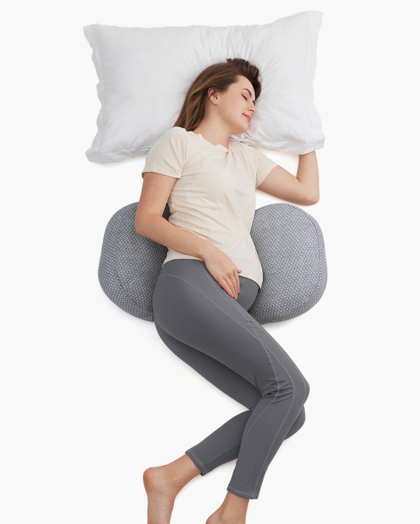 Pregnant woman sleeping on her side with the Momcozy wedge pillow under her bump
