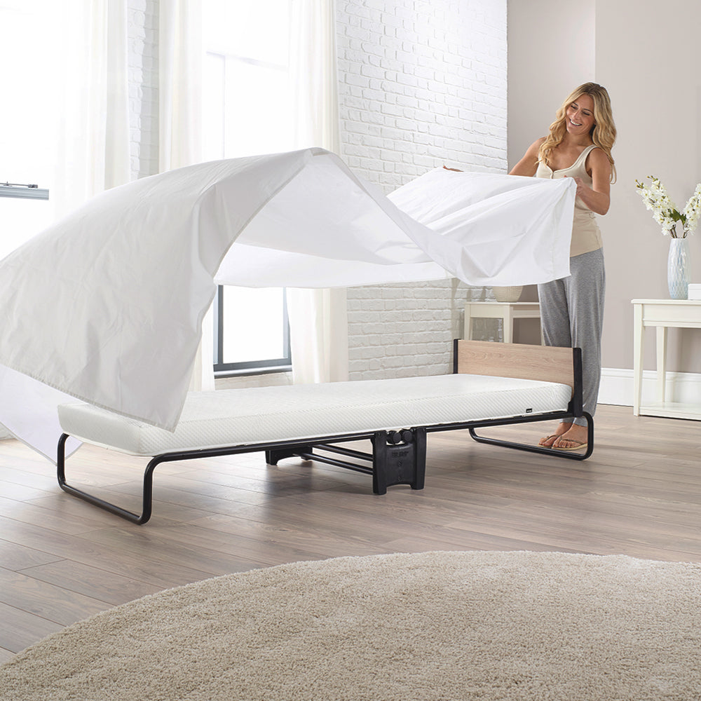 Woman making up the Jay-Be Revolution Folding Bed with a white sheet