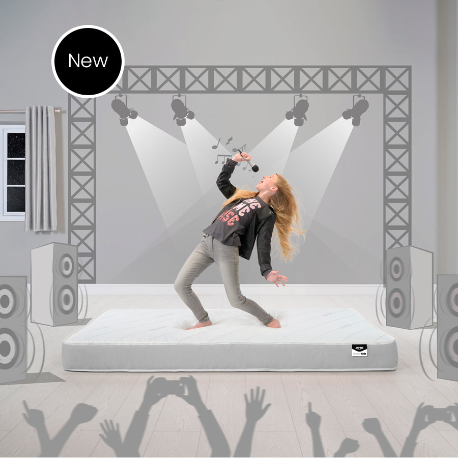 Child playing on a Jay-Be Simply Kids mattress in a stage-themed room