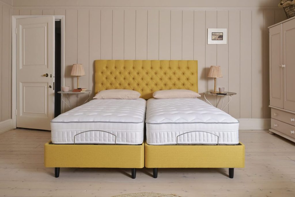 Two Sleepeezee InMotion Eco mattresses side by side on a yellow upholstered adjustable divan