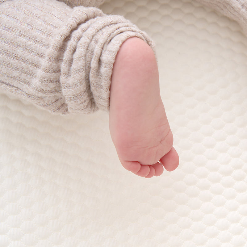 Close-up of the Tiny Dreamer bubble-knit mattress cover with a baby foot